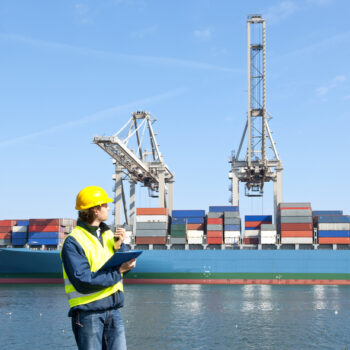 Docker examining a container vessel, with a clipboard and cb radio in his hands