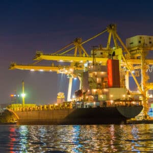 Container Cargo freight ship with working crane bridge in shipyard